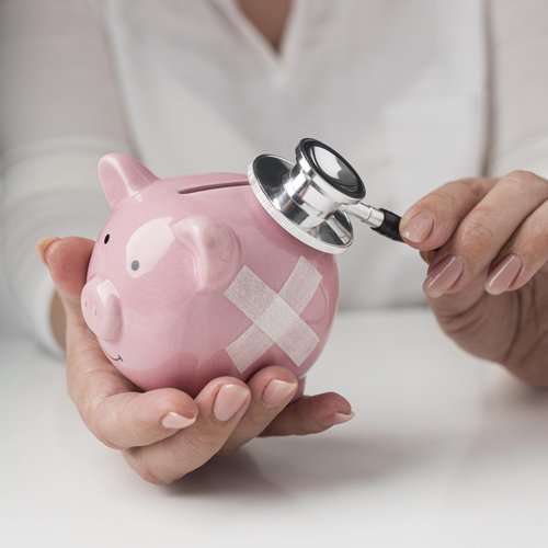 person-putting-stethoscope-piggy-bank